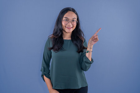 Asian Indonesian woman wearing green dress and pointing to the sideの写真素材