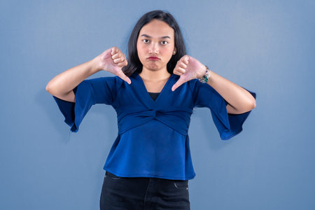 Indonesian Asian woman in blue dress shows dislikeの写真素材