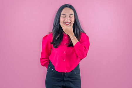 Indonesian Asian woman wearing red shirt smiling and holding her chin