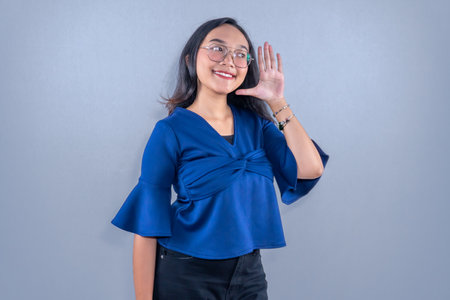 Asian woman wearing blue shirt smiling and signalingの写真素材