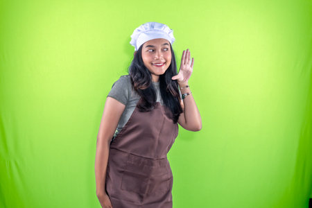Indonesian Asian woman wearing brown cooking clothes whispering to the sideの写真素材