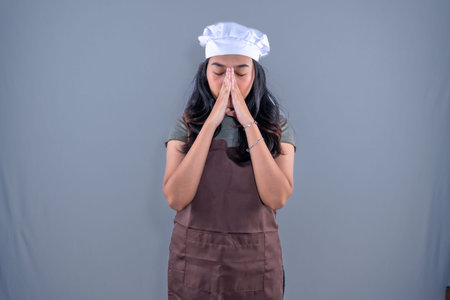 Asian Indonesian woman wearing cooking clothes is disappointed or confusedの写真素材
