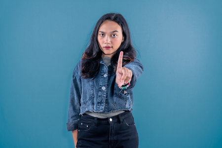 Indonesian Asian woman wearing blue jean jacket giving a signal not to mess around