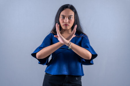 Indonesian Asian woman wearing a long-sleeved blue shirt giving a sign of disagreement
