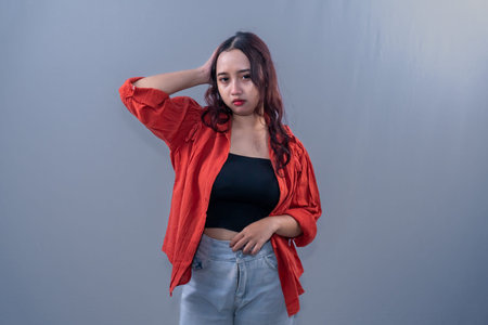 An Indonesian Asian woman in orange is holding her head.