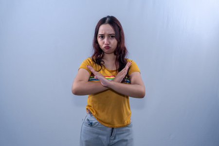 Indonesian Asian woman in yellow dress gives a sign of disagreement