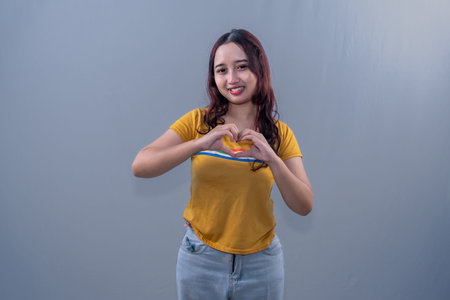 Indonesian Asian woman in yellow dress smiling and making love sign