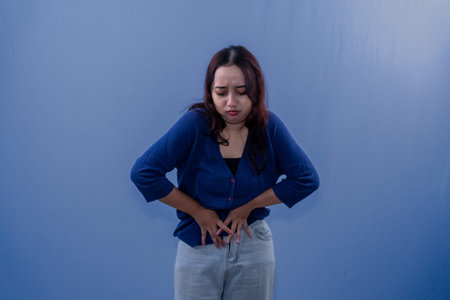 Indonesian Asian woman in blue dress having stomach ache