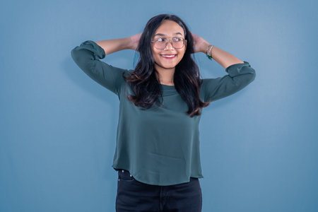 Indonesian Asian woman wearing blue clothes smiling and holding her head with both hands