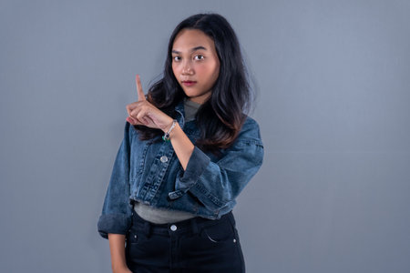 Indonesian Asian woman wearing blue jeans jacket giving warning code to someoneの写真素材