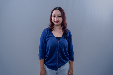 Asian Indonesian woman wearing blue clothes standing straight and smilingの写真素材