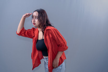 An Indonesian Asian woman wearing an orange dress is looking at something far away.の写真素材