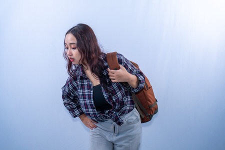 Asian Indonesian woman wearing plaid shirt carrying backpack looking down