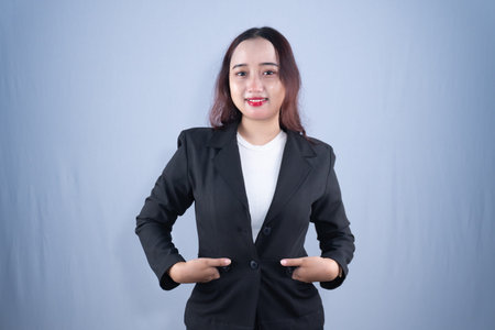 A young woman in a black blazer and white shirt poses confidently while smiling at the camera in a...