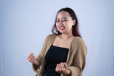 Asian Indonesian woman wearing brown cardigan smiling with successful expression