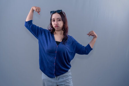 Asian Indonesian woman wearing blue clothes raising her hands in celebration of success