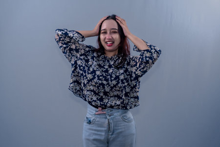 Indonesian Asian woman wearing black floral patterned dress smiling and holding her head