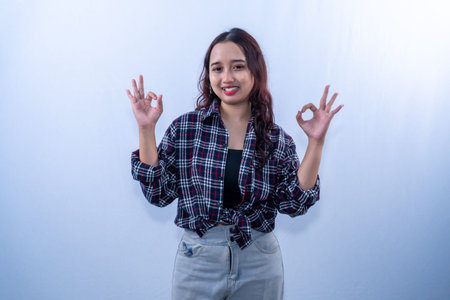 Indonesian Asian woman wearing a checkered shirt smiling and giving an okay sign