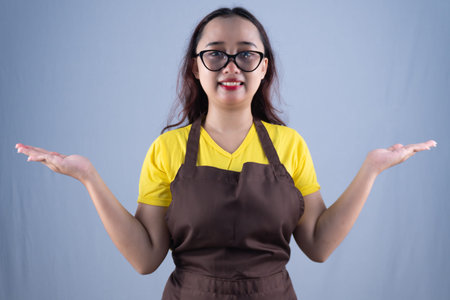 A woman in glasses and an apron stands, smiling, with open hands