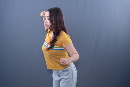 Young woman in striped yellow t-shirt, light jeans, looking distressed, hand to head