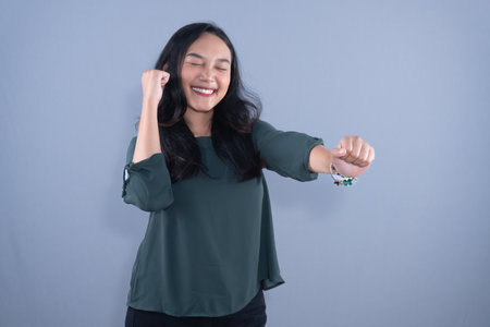 A smiling young woman with her eyes closed, clenching her fists in a gesture of victory.の写真素材