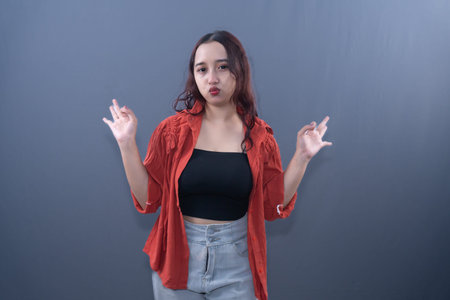 A pouting woman in a red shirt and black top makes an air quotes gesture with her hands.