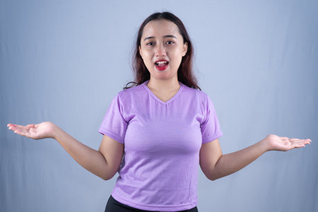 A woman in a purple shirt with an open mouth and palms up in a what's the deal gesture.の写真素材