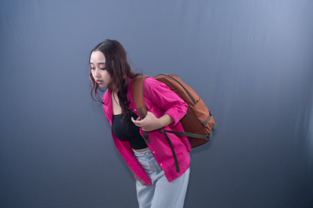 A woman with a backpack, bent over, looks in discomfort or pain.の写真素材