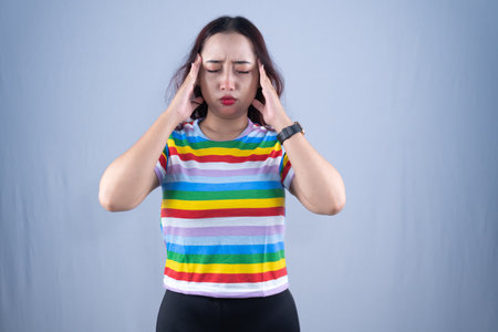 A woman is wearing a rainbow shirt and a watch against a gray backgroundの写真素材