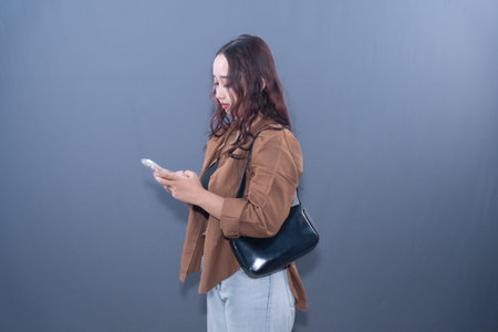 A woman in a brown shirt is looking intently at her smartphone