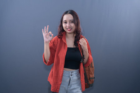 A smiling woman in an orange shirt makes a hand gesture