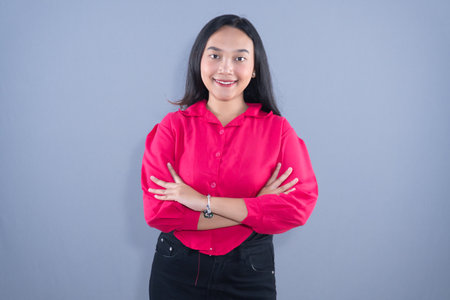 A smiling woman in a pink shirt stands with arms crossedの写真素材