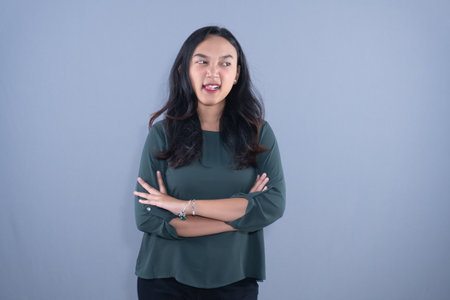 A woman in a green top stands with arms crossedの写真素材