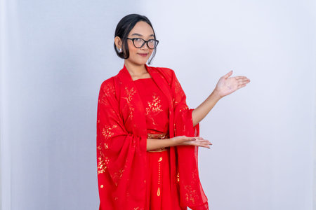 A young woman in a traditional red Chinese outfit is posing, presenting somethingの写真素材