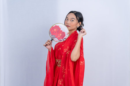 A beautiful woman in a red traditional dress and holding a floral fanの写真素材