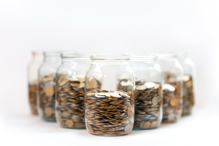 coins in a three glass jars against a white backgroundの写真素材