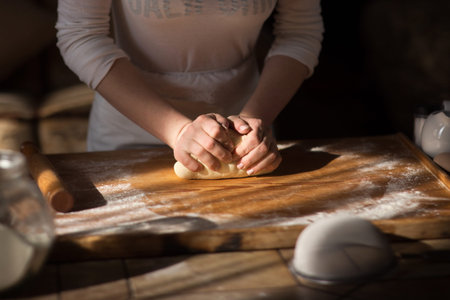 Baker hands kneading dough in flour on table