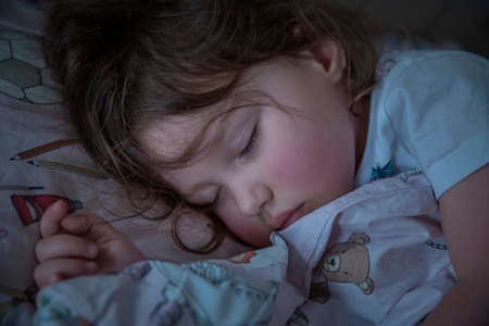 Adorable 3 years old baby girl sleeping in her bedの写真素材