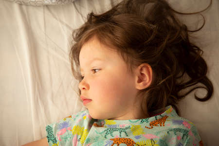 Adorable little girl laying in her bedの写真素材
