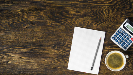 Dark wooden table. Calculator. Pencil and coffee cardの写真素材