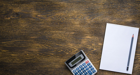 Dark wooden table, calculator and pencilの写真素材