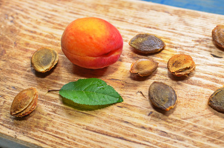 Ripe apricots and apricot leaves on the wooden background.
