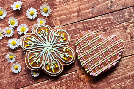Ginger cookies lie on a wooden background. Christmas sweetness. In addition to chamomile flowers.