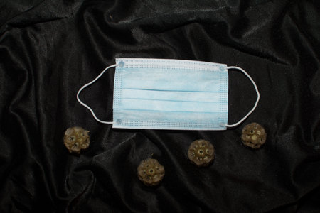 Protective medical mask on dark background. Typical 3-ply surgical mask to cover the mouth and nose....