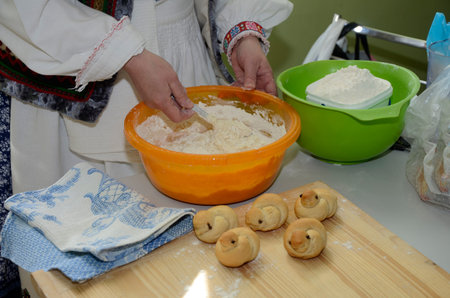 A woman in a national suit will mix the dough with her hands. Baking traditional birds (skylark)...