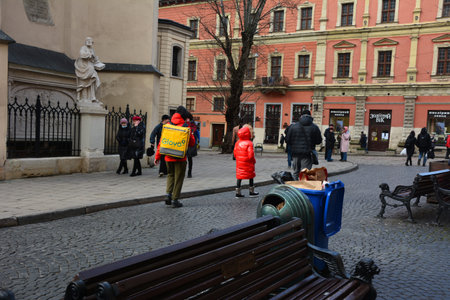 Lviv, Ukraine - January 2021: A deliveryman for Glovo in center of Lviv. Ukraine shutdowns bars, restaurants and shopping malls to stem the spread of the coronavirus.のeditorial素材