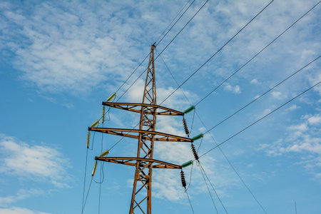 Looking up steel power pylon construction with high voltage cables against blue sky. Single power...