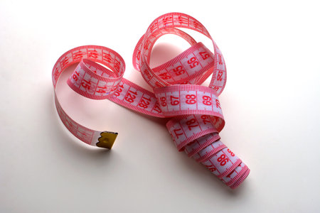 Tape measure on white background .Pink metric measuring tape on white background .の写真素材
