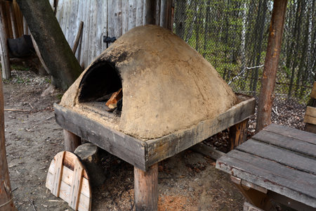 wood-burning stove with food in pots. Smoky antique brick oven outdoor with firewood and a benchの写真素材