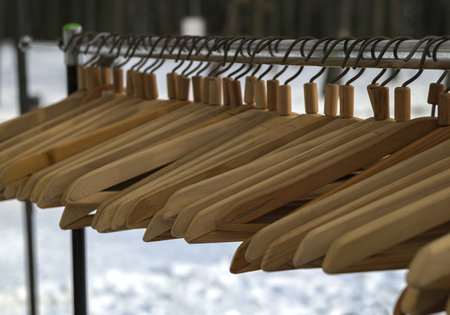 Many wooden hangers on a rod. Store concept, sale, design, empty hangers. Black Friday. Wooden coat hanger clothes. Fashionable different types of hanger. Wood Hangers coat. Blurred focus.の写真素材